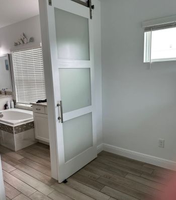 Modern bathroom with white frosted glass door and vanity in a light gray room
